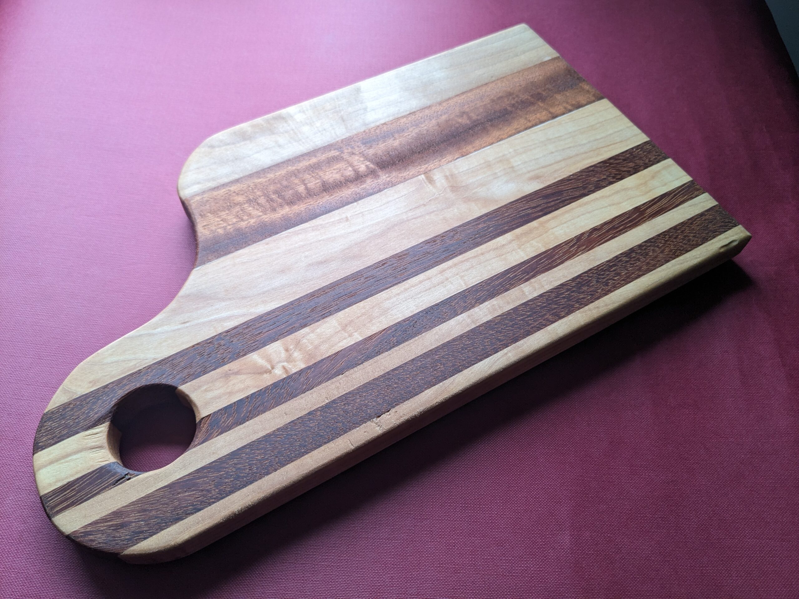 Handmade striped cutting or serving board with hanging feature